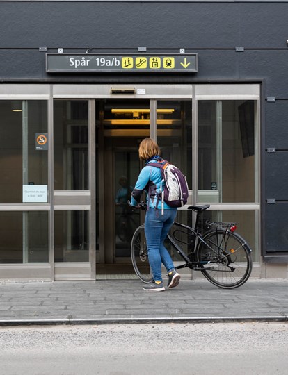 Kvinna på väg med cykel till spåret vid Stockholm centralstation