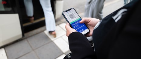 Närbild på person med digital biljett vid buss