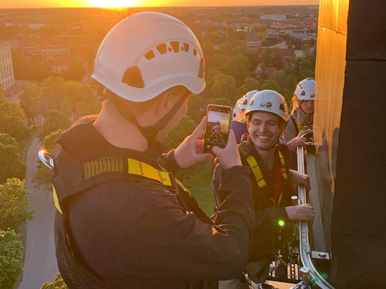 Person som fotar med sin mobiltelefon på taket under en stadsvandring i Uppsala